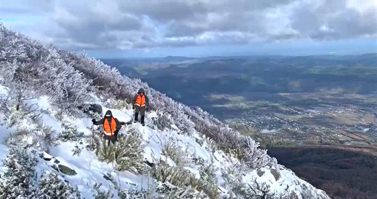 Cerro Malalcura cubierto de nieve, con dos exploradores avanzando sobre él.