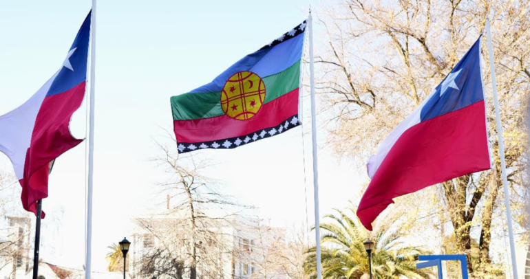 La bandera flameando entre dos estandartes chilenos, frente a la delegación. Foto de archivo: Mindeso Ñuble.